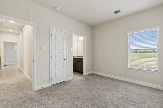 unfurnished bedroom featuring light colored carpet and ensuite bath