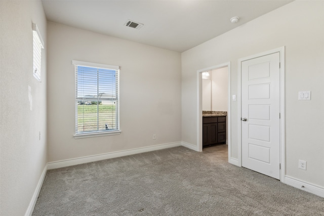 unfurnished bedroom featuring ensuite bath and light carpet