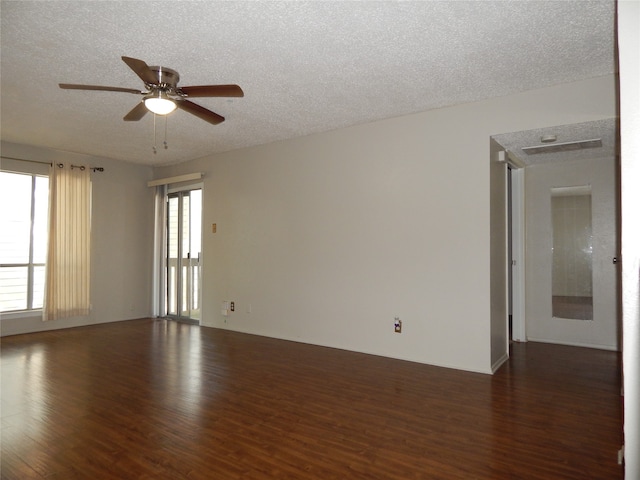 empty room featuring a textured ceiling, dark hardwood / wood-style floors, ceiling fan, and plenty of natural light