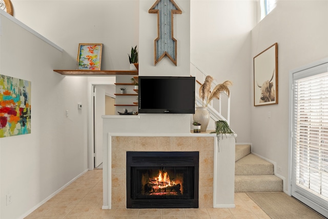 living room with a high ceiling, a fireplace, and light tile patterned flooring