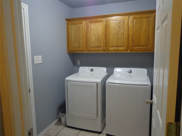 washroom with cabinets, light tile patterned floors, and washing machine and clothes dryer