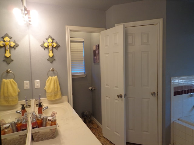 bathroom featuring tiled tub and vanity