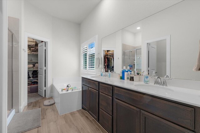 bathroom featuring wood-type flooring, vanity, and plus walk in shower