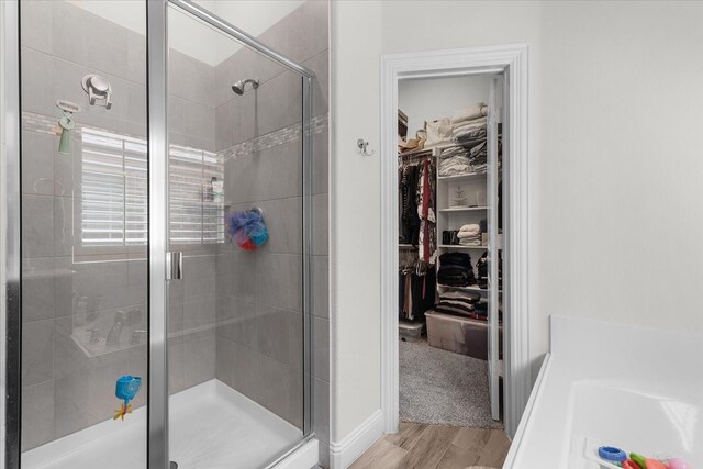 bathroom featuring plus walk in shower and hardwood / wood-style flooring