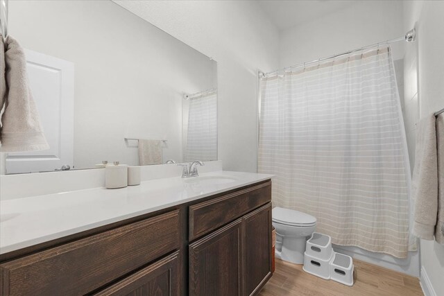 full bathroom featuring vanity, hardwood / wood-style floors, toilet, and shower / bathtub combination with curtain