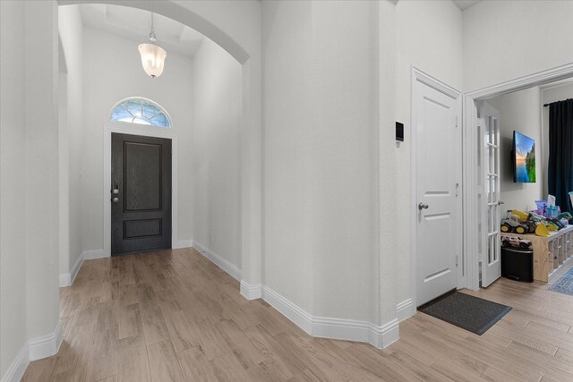 entryway featuring light wood-type flooring and a towering ceiling