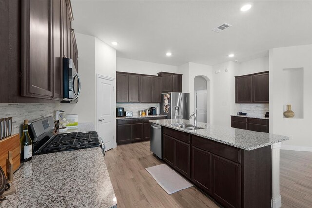 kitchen with appliances with stainless steel finishes, light hardwood / wood-style floors, sink, and an island with sink