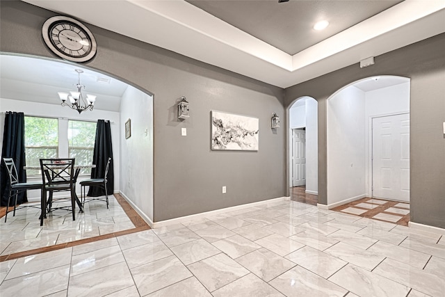 unfurnished dining area with a raised ceiling and an inviting chandelier