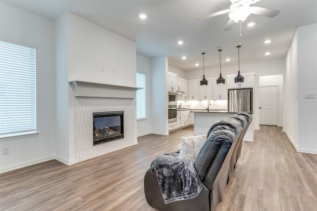 living room with ceiling fan, sink, and light hardwood / wood-style flooring