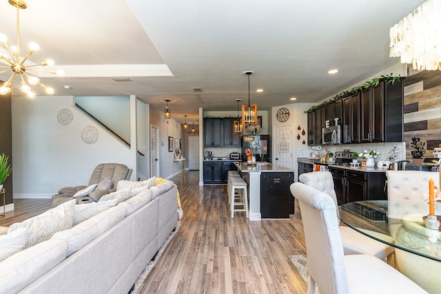 kitchen featuring hanging light fixtures, light hardwood / wood-style flooring, stainless steel appliances, a center island, and a kitchen bar