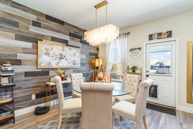 dining space featuring wood walls, an inviting chandelier, and hardwood / wood-style flooring