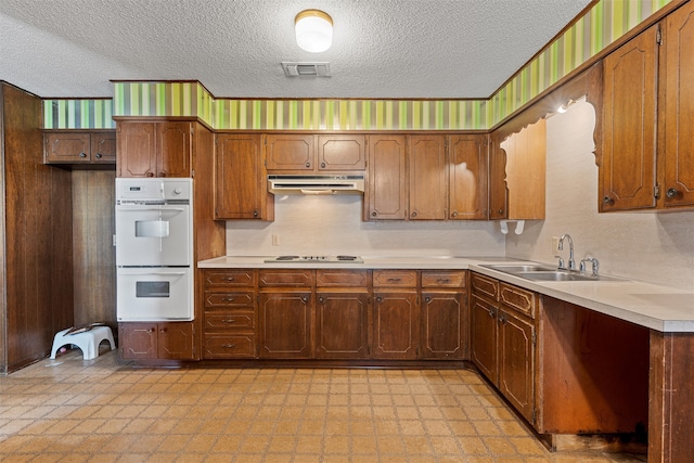 kitchen with a textured ceiling, sink, and white appliances