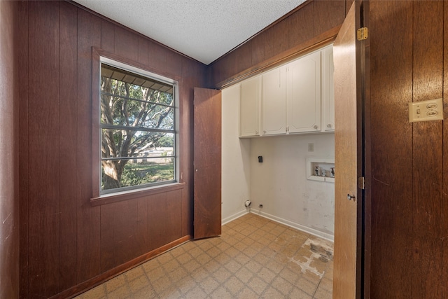 washroom featuring cabinets, hookup for an electric dryer, a textured ceiling, wood walls, and hookup for a washing machine