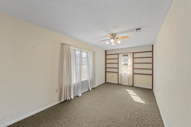 carpeted empty room with ceiling fan, a textured ceiling, and a healthy amount of sunlight