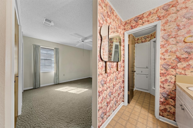 bathroom with ceiling fan, vanity, and a textured ceiling