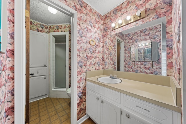 bathroom with a textured ceiling, vanity, toilet, and a shower with door