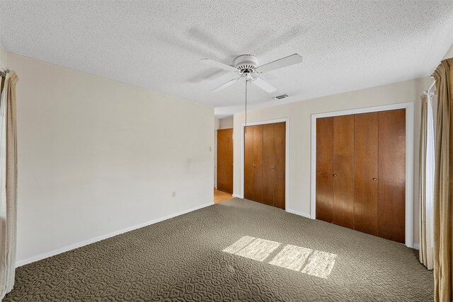 unfurnished bedroom with multiple closets, ceiling fan, carpet flooring, and a textured ceiling