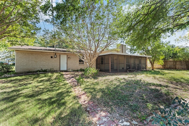 rear view of house featuring a yard and a sunroom