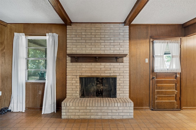 unfurnished living room featuring a brick fireplace, a textured ceiling, and wood walls