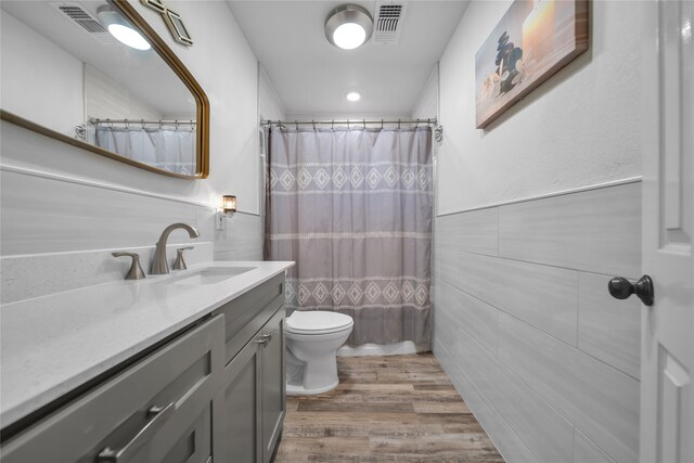 bathroom featuring toilet, wood-type flooring, tile walls, a shower with shower curtain, and vanity