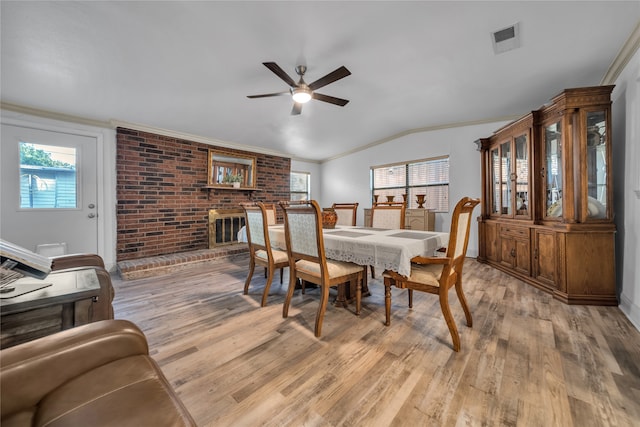 dining area with a fireplace, ornamental molding, light hardwood / wood-style flooring, and ceiling fan