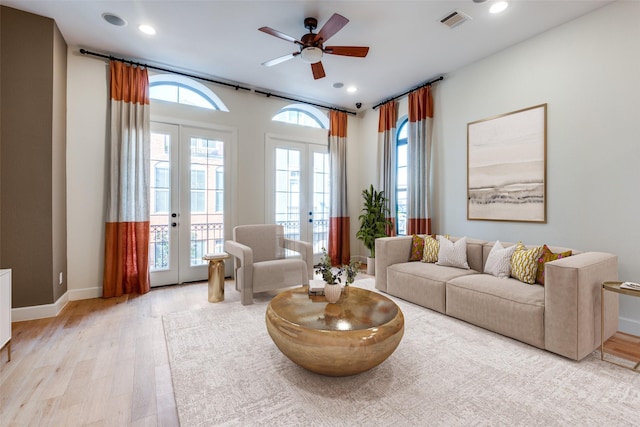 living room featuring ceiling fan, a healthy amount of sunlight, light hardwood / wood-style flooring, and french doors