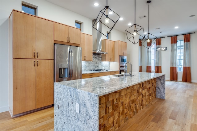 kitchen featuring sink, hanging light fixtures, appliances with stainless steel finishes, a large island, and light stone counters