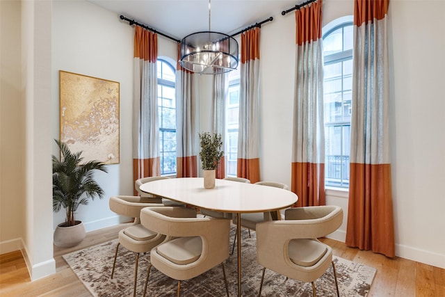 dining room with a wealth of natural light, light hardwood / wood-style flooring, and a notable chandelier