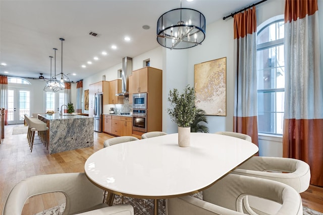 dining area with sink, a notable chandelier, plenty of natural light, and light hardwood / wood-style floors