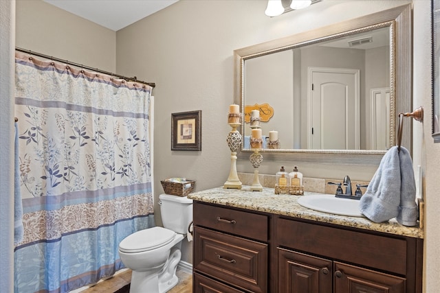 bathroom with curtained shower, vanity, and toilet