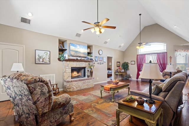 living room with hardwood / wood-style floors, ceiling fan, a stone fireplace, and high vaulted ceiling