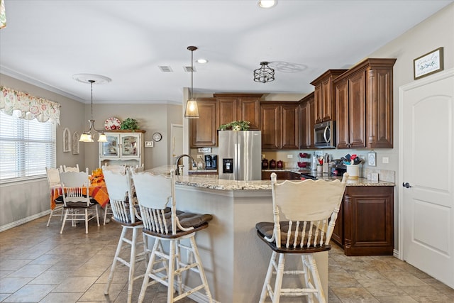 kitchen featuring a large island, stainless steel appliances, light stone counters, decorative light fixtures, and a breakfast bar