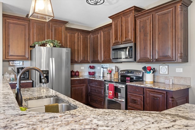 kitchen with light stone countertops, sink, stainless steel appliances, and decorative light fixtures