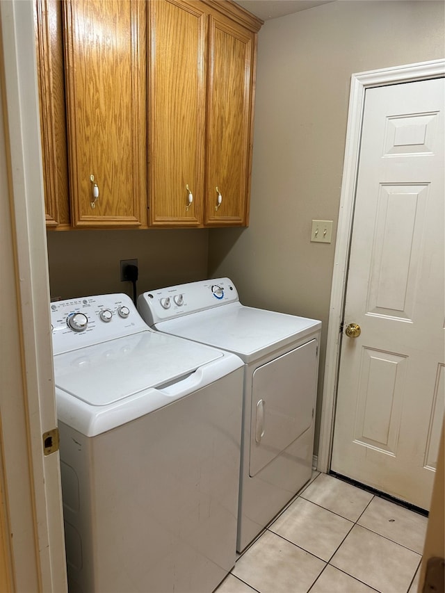 washroom with cabinets, light tile patterned floors, and washing machine and clothes dryer