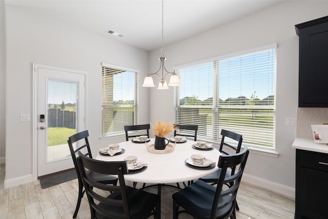 dining room with light wood-type flooring, plenty of natural light, and a chandelier