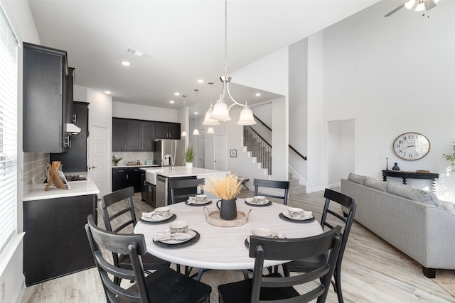 dining area with ceiling fan with notable chandelier and light hardwood / wood-style flooring