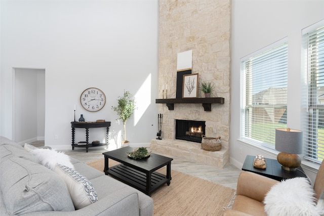 living room with a high ceiling, light parquet floors, a healthy amount of sunlight, and a stone fireplace