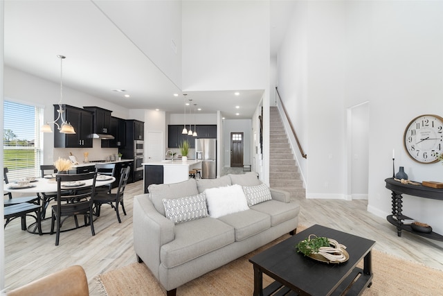 living room featuring a high ceiling, light wood-type flooring, and sink