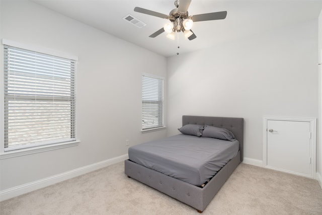 bedroom with ceiling fan, light colored carpet, and multiple windows