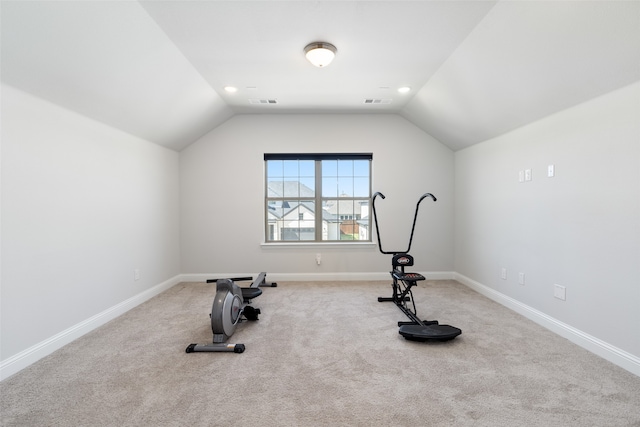 workout area with vaulted ceiling and light carpet