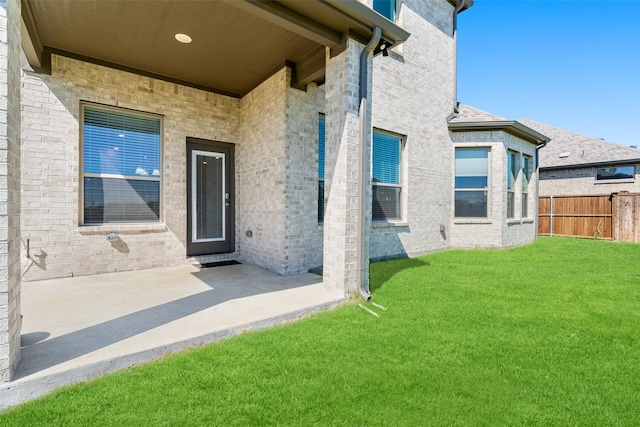 view of exterior entry with a patio and a yard