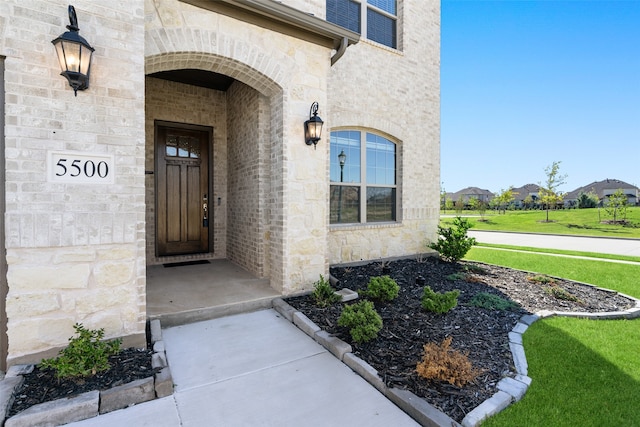 view of exterior entry featuring a lawn