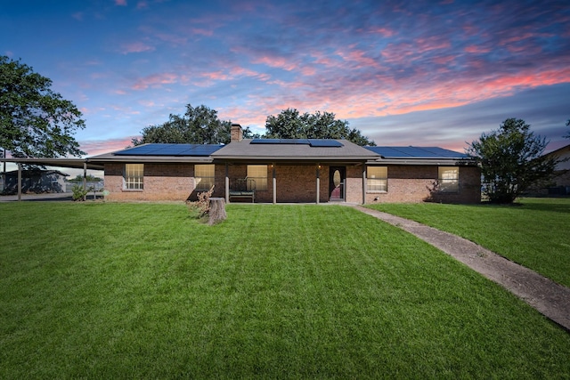 back house at dusk featuring a yard and solar panels