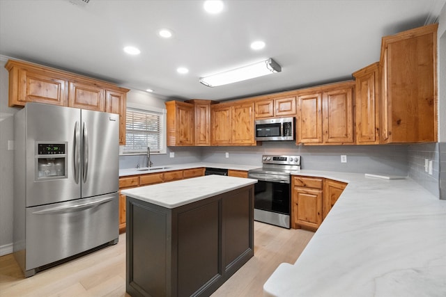 kitchen featuring appliances with stainless steel finishes, a center island, sink, and light hardwood / wood-style flooring