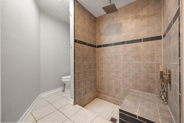 bathroom featuring a tile shower, tile patterned floors, and toilet