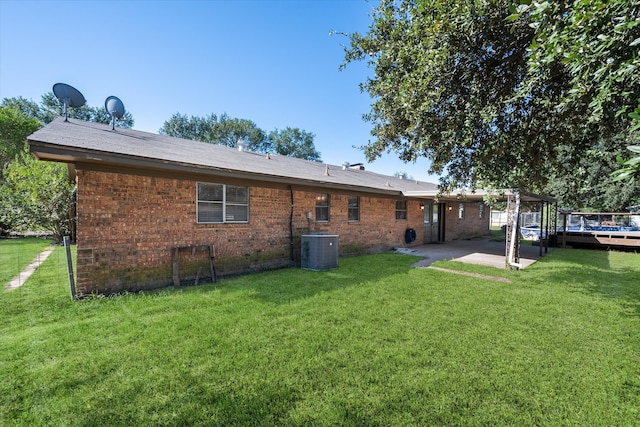 rear view of property featuring central AC unit, a yard, and a patio area