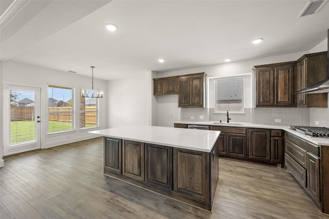 kitchen with a center island, hardwood / wood-style flooring, sink, pendant lighting, and stainless steel gas cooktop