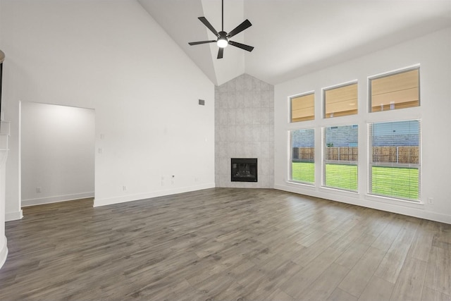 unfurnished living room with a tile fireplace, wood finished floors, baseboards, high vaulted ceiling, and ceiling fan