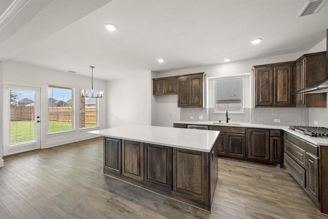 kitchen featuring backsplash, light wood finished floors, stainless steel gas cooktop, and a sink