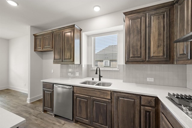kitchen featuring stainless steel appliances, light countertops, dark brown cabinets, a sink, and tasteful backsplash